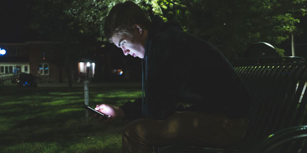 A young person sat by themselves at night on a park bench