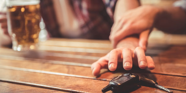 Someone reaching for a set of car keys and being prevented by a friend